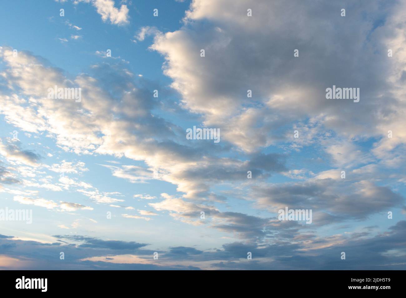 Sfondo blu cielo con morbide nuvole di cumuli illuminate dal sole che tramonta. Panorama di nuvole bianche e soffici nel cielo blu. Bella vasta blu sk Foto Stock