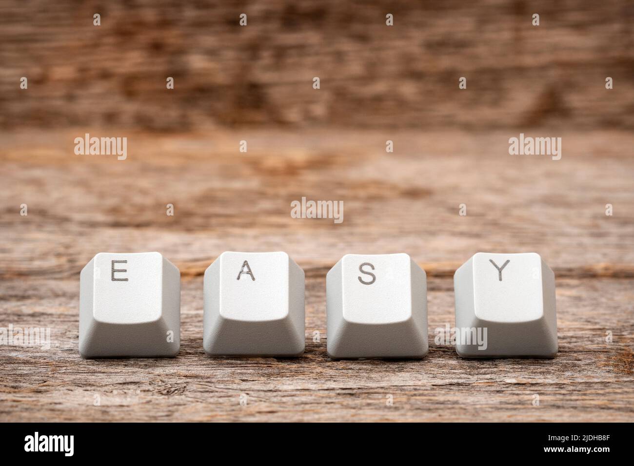 Tasti della tastiera del computer disposti per scrivere PAROLE FACILI sullo sfondo di legno Foto Stock