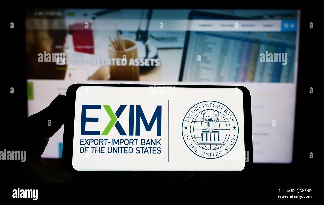 Persona che tiene uno smartphone con il logo della Export-Import Bank of the United States (Exim) sullo schermo di fronte al sito Web. Mettere a fuoco sul display del telefono. Foto Stock