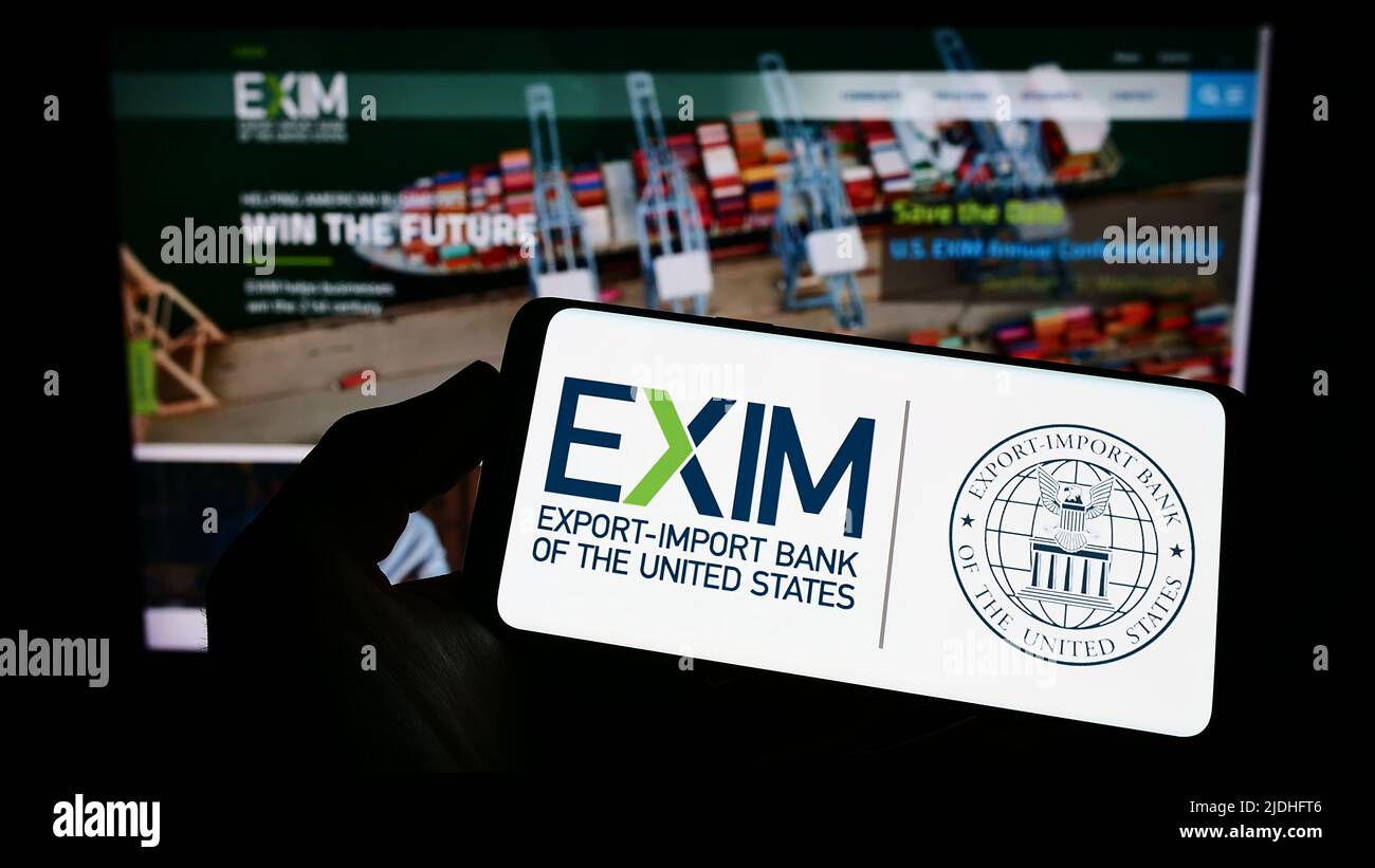 Persona che tiene il cellulare con il logo di Export-Import Bank of the United States (Exim) sullo schermo di fronte al sito web. Mettere a fuoco sul display del telefono. Foto Stock