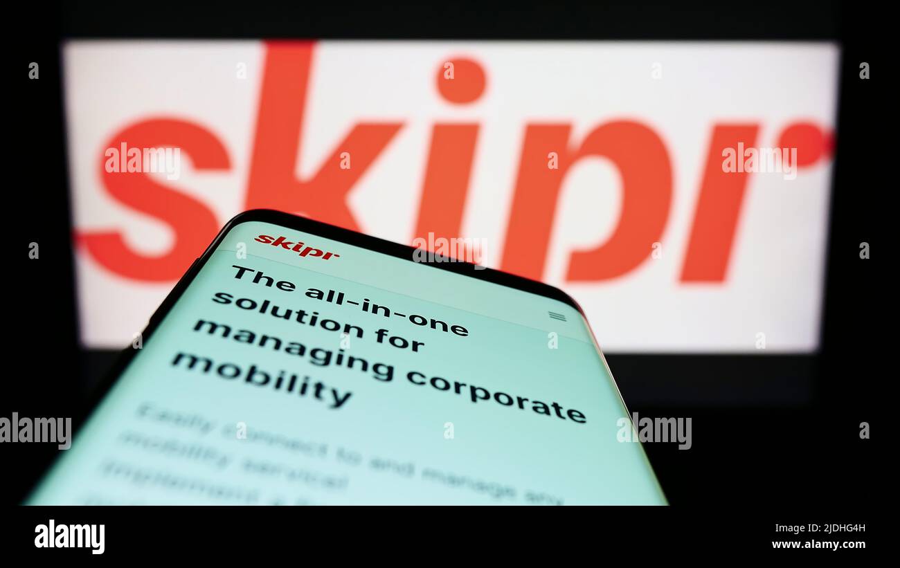 Smartphone con sito web della società di mobilità belga Skipr SA sullo schermo di fronte al logo aziendale. Mettere a fuoco sulla parte superiore sinistra del display del telefono. Foto Stock