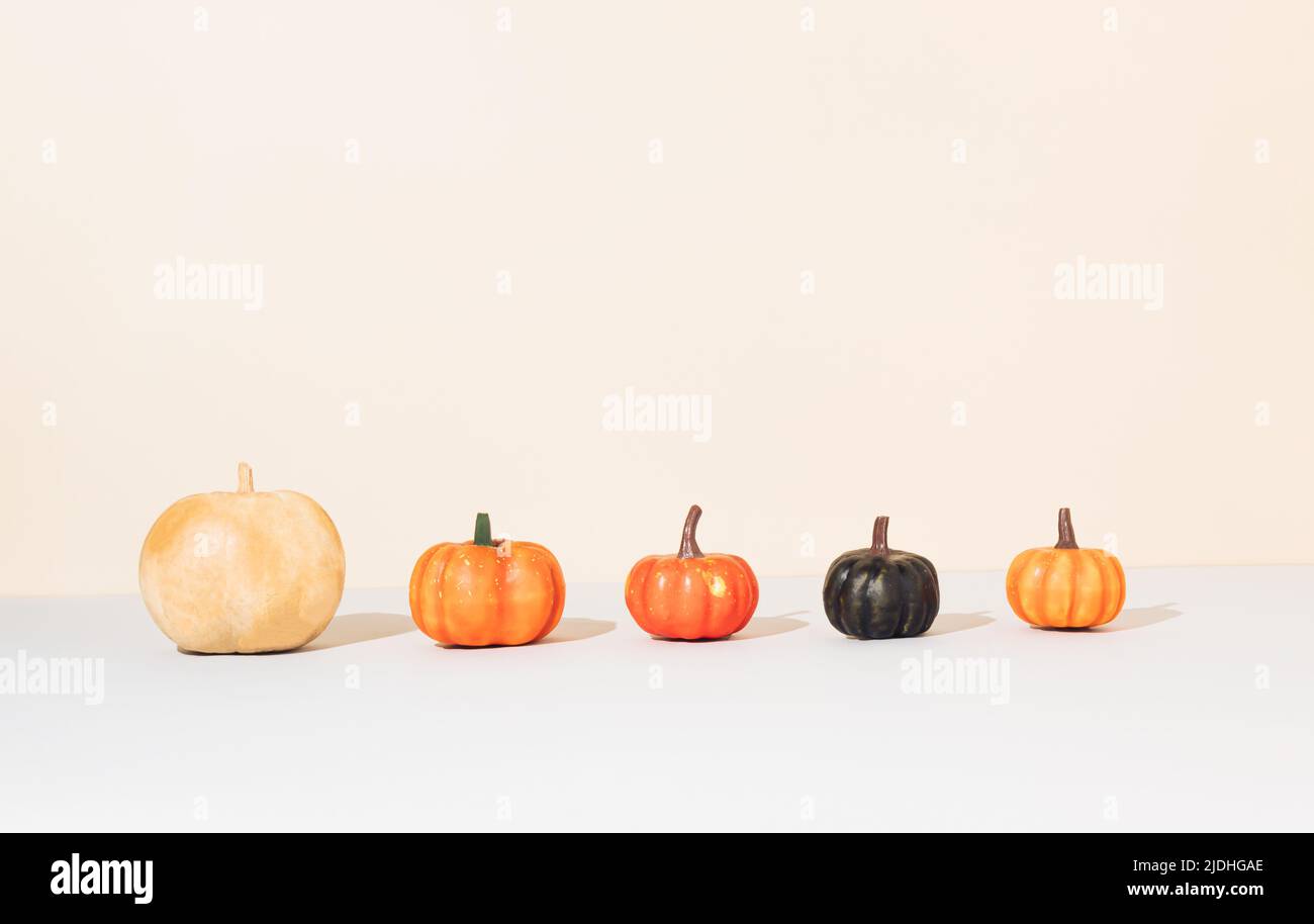 Creativo layout autunnale realizzato con zucche colorate su sfondo beige con spazio copia. Halloween natura concetto. Estetica moderna. Foto Stock