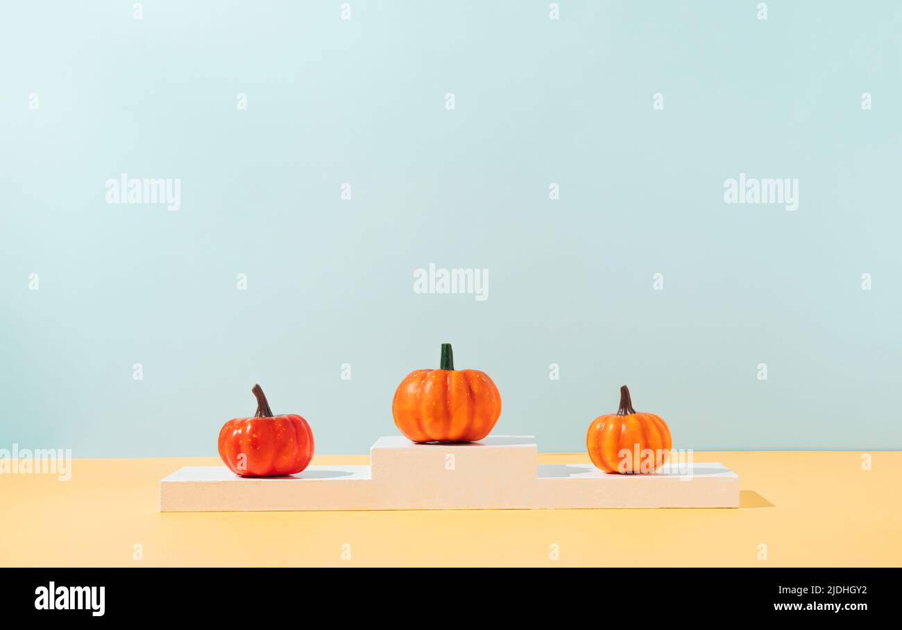 Concetto creativo composto da colorate zucche autunnali in piedi sul podio vincente. Idea minima di Halloween con spazio di copia. Estetica moderna. Foto Stock Concetto creativo composto da colorate zucche autunnali in piedi sul podio vincente. Idea minima di Halloween con spazio di copia. Estetica moderna. Foto Stock
