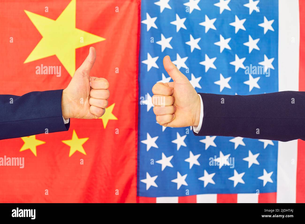 I politici cinesi e americani raggiungono un accordo e danno il pollice in su, con le bandiere sullo sfondo Foto Stock