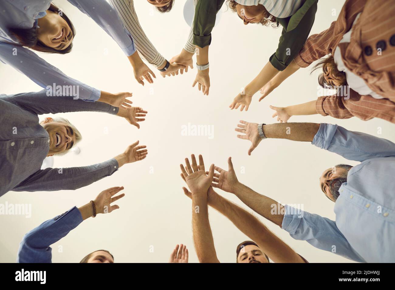 Vista dal basso del team di persone aziendali che si trovano in piedi insieme e che si uniscono alle loro mani Foto Stock