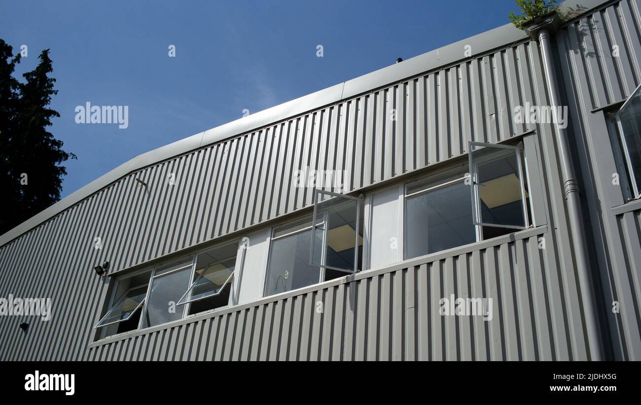 Le finestre degli uffici si aprono in un complesso industriale di uffici in una calda giornata di sole. Foto Stock