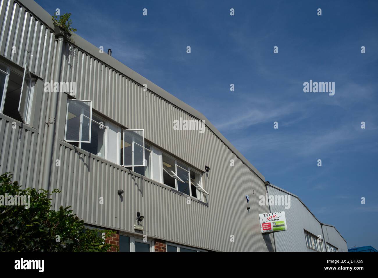 Le finestre degli uffici si aprono in un complesso industriale di uffici in una calda giornata di sole. Foto Stock
