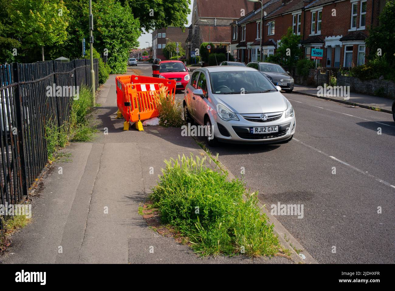 Un marciapiede bloccato da una barriera di plastica che nasconde un ceppo di albero nella città di Eastleigh. Foto Stock