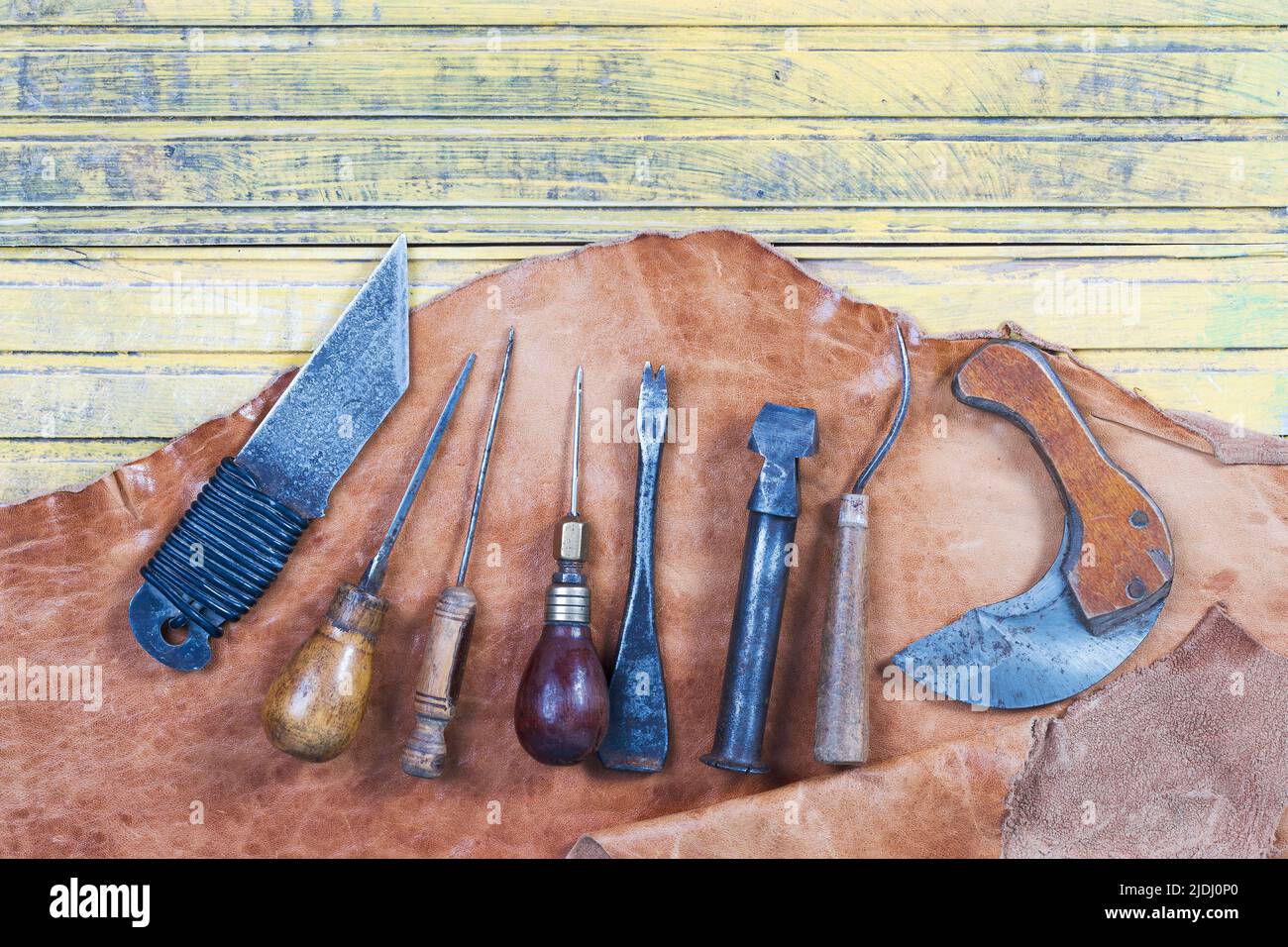 Attrezzi di mestiere di cuoio su uno sfondo di legno. Scrivania artigianale in pelle . Pezzo di cuoio e di attrezzi di lavoro fatti a mano su un tavolo di lavoro Foto Stock