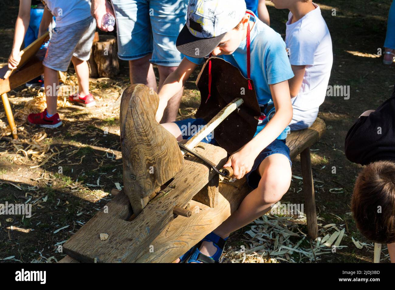 Bambino ragazzo che rasa ramo di legno con attrezzi tradizionali al Tunderfesztival 2022, Sopron, Ungheria Foto Stock