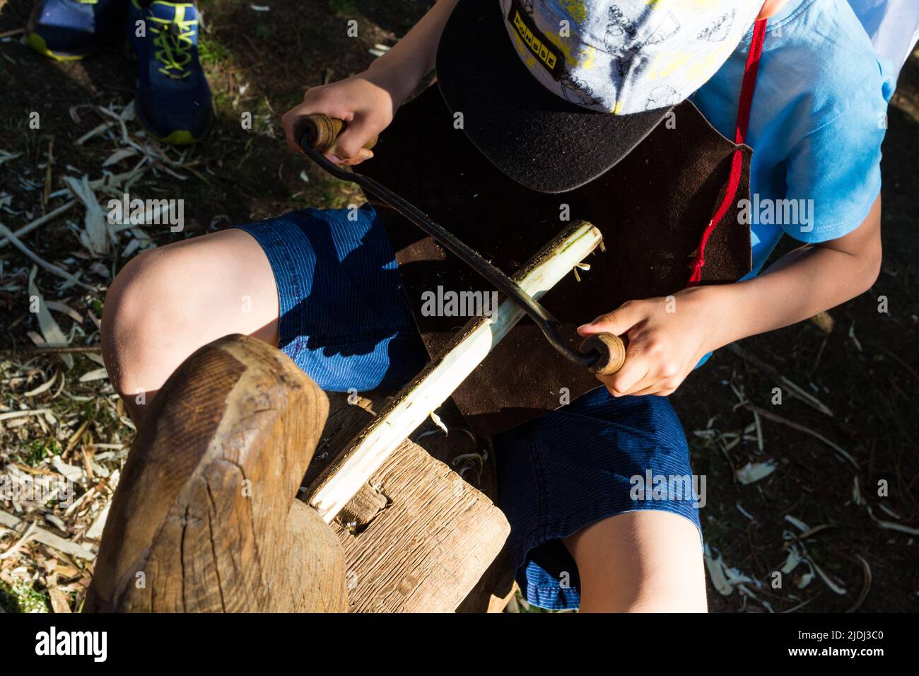 Bambino ragazzo che rasa ramo di legno con attrezzi tradizionali al Tunderfesztival 2022, Sopron, Ungheria Foto Stock