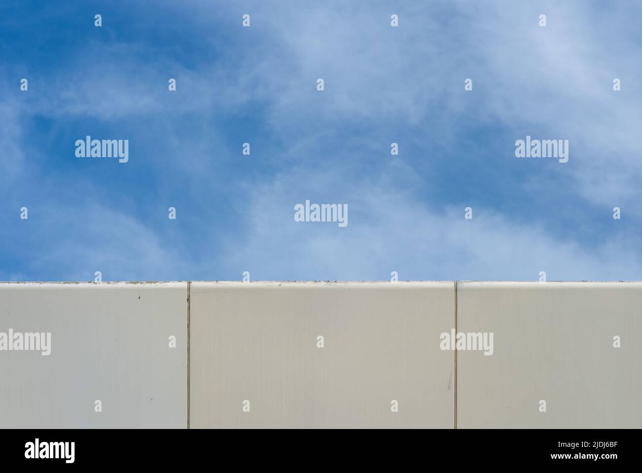 Immagine astratta, l'angolo di un edificio moderno che contrasta con il cielo blu e le nuvole bianche. Foto Stock