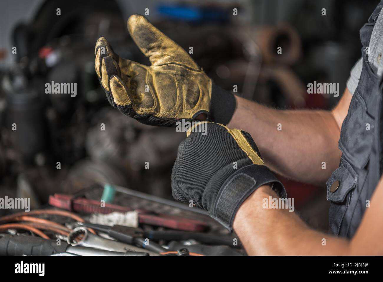 Primo piano dei guanti da lavoro sporchi del meccanico caucasico dopo una giornata di duro lavoro alla stazione di officina. Tema automobilistico. Foto Stock