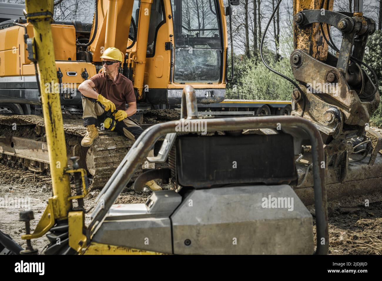 Operatore di attrezzature da costruzione per lavori al suolo seduto su una macchina per escavatori per impieghi gravosi che si rompa dopo aver completato il lavoro. Settore edile T Foto Stock