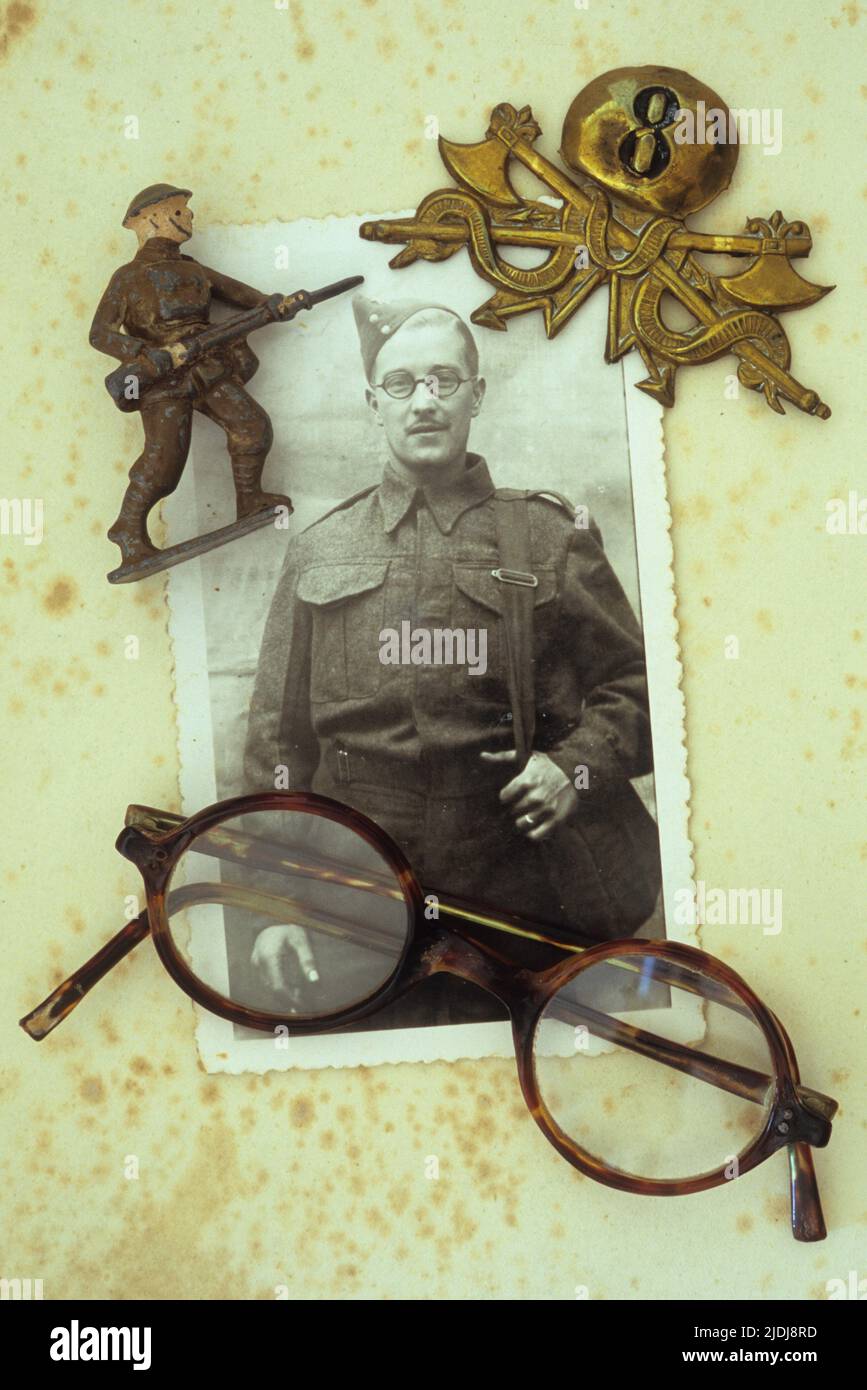 Foto vintage in bianco e nero dell'uomo nella divisa dell'esercito della Guerra Mondiale 2 che giace con i suoi occhiali 8th badge dell'esercito e modello di piombo soldato Foto Stock