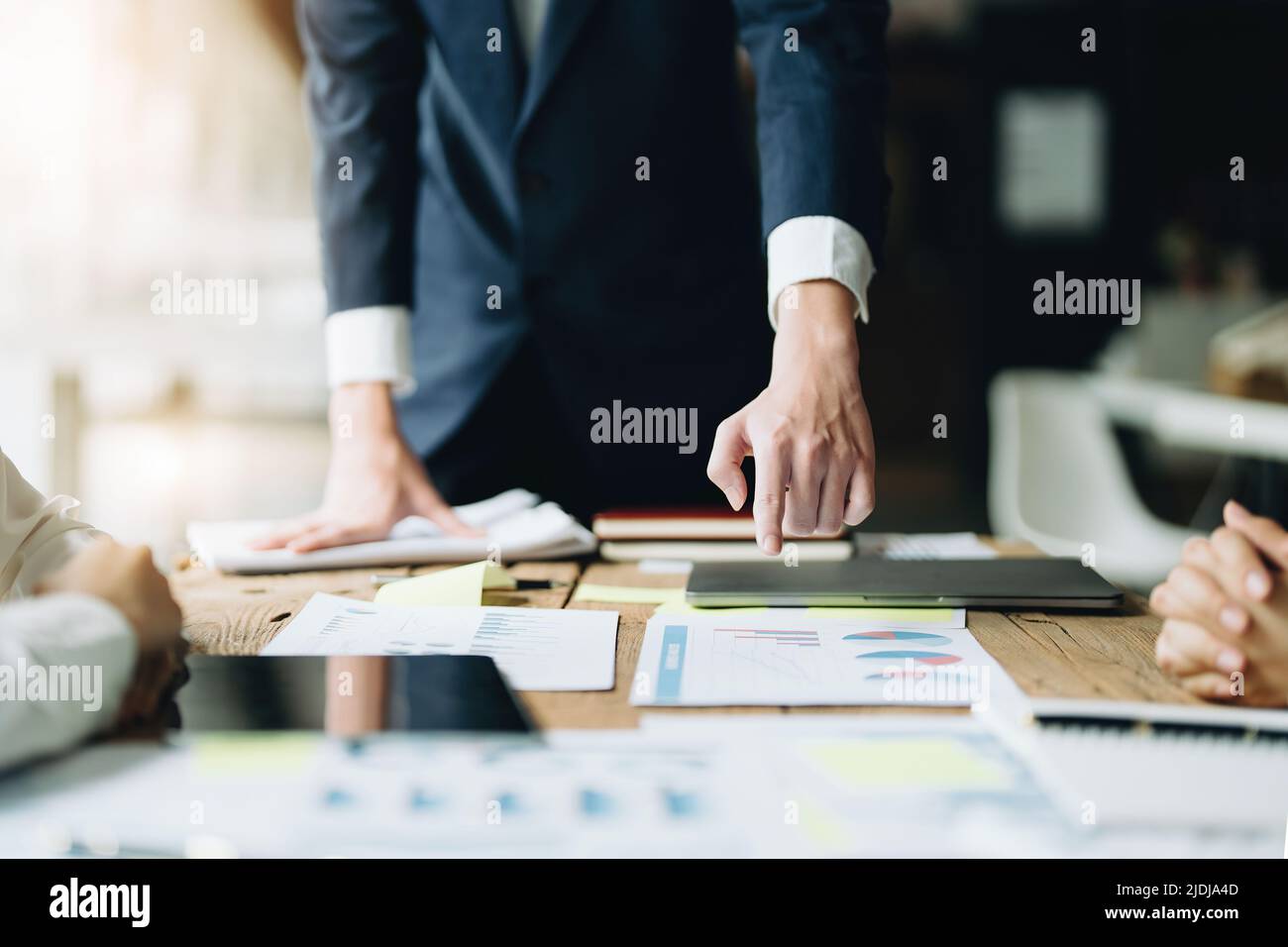 Uomo d'affari maschile che punta a documenti che riassumono la strategia di marketing con colleghi femminili in riunione, lavoro di squadra, pianificazione degli investimenti Foto Stock