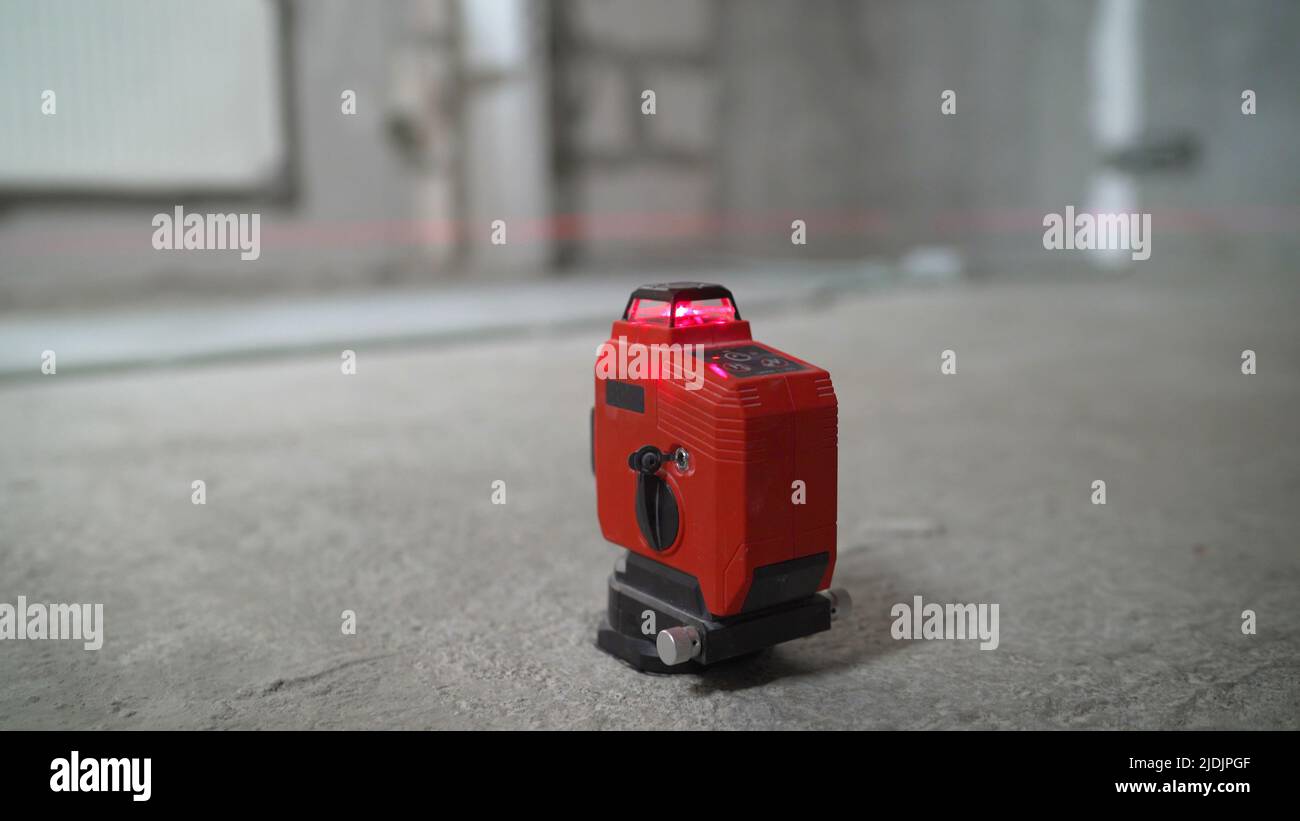 Livella laser in funzione. Livella laser e pareti e pavimenti in calcestruzzo. Ristrutturazione dell'appartamento. Foto Stock
