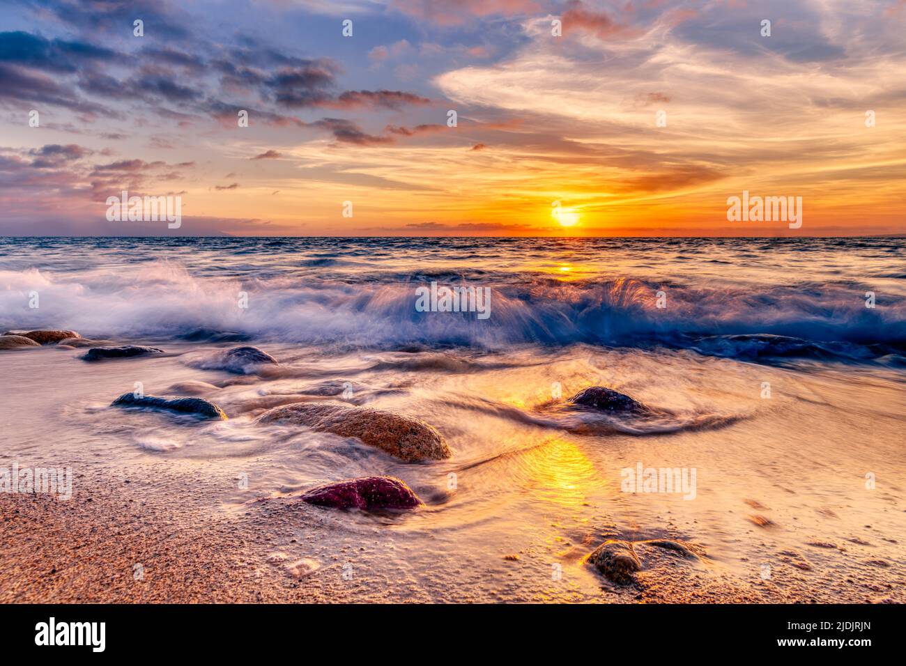 Il sole sorge come un'onda spruzza su Una colorata spiaggia tropicale ad alta risoluzione Foto Stock