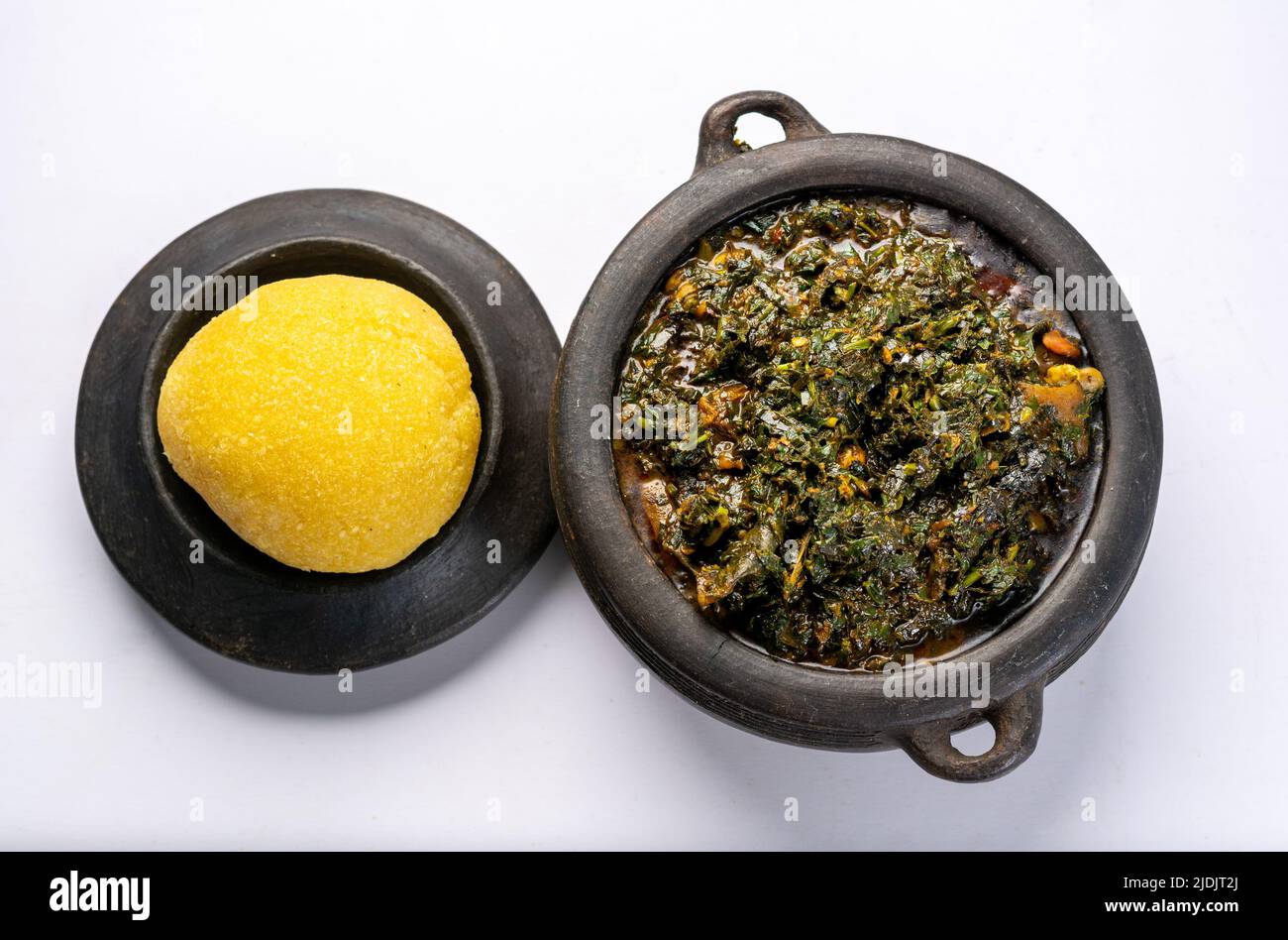 Efik Afang zuppa nigeriana servita in una ciotola di argilla con garri Foto Stock