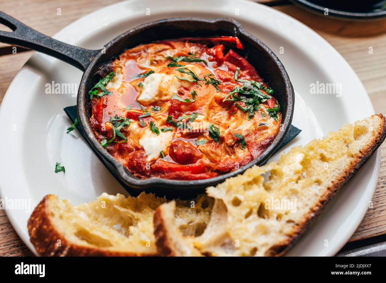 Shakshuka in padella di ferro servito con pane Foto Stock