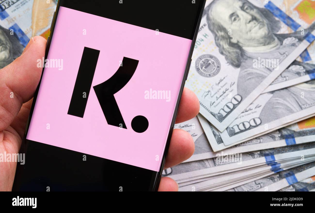 Il logo dell'app Klarna visto sullo schermo dello smartphone tiene una mano e sulle bollette del dollaro. Stafford, Regno Unito, giugno 19 2022 Foto Stock