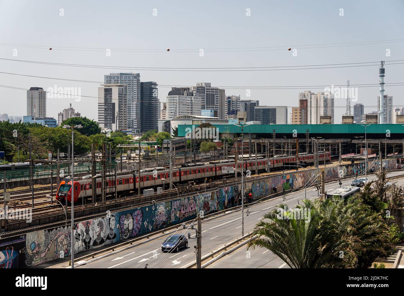 Vista distante della stazione di Palmeiras-barra Funda mentre un treno pendolare CAF Serie 8000 (S080) CPTM arriva ad esso in un cielo blu soleggiato normale. Foto Stock