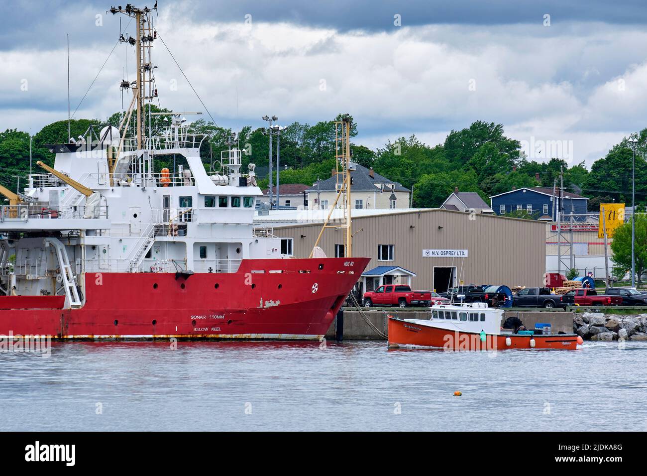 Interessante contrasto nelle dimensioni di queste due barche nel porto a North Sydney Cape Breton Nova Scotia rende per una fotografia interessante. Foto Stock