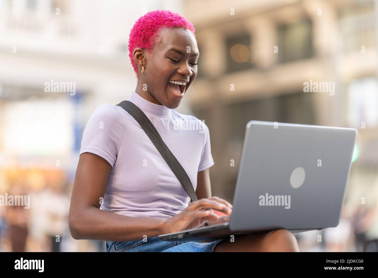 Felice donna africana che usa il portatile per strada Foto Stock