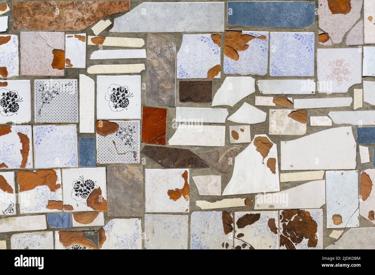 Lo sfondo sotto forma di pezzi di antiche piastrelle ceramiche diverse posate su intonaco di calcestruzzo. Foto Stock