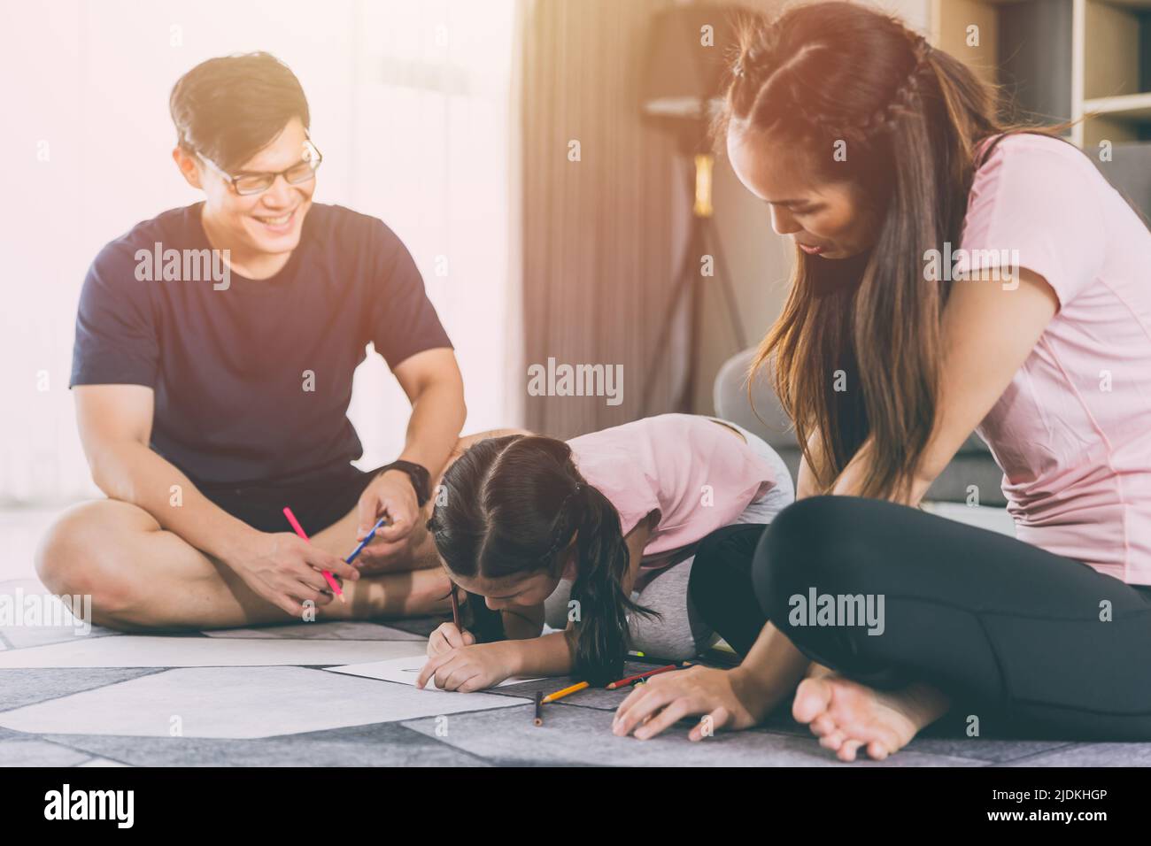 Famiglia asiatica genitori giocare con la figlia in soggiorno insieme bambino disegno cartone animato in carta. Foto Stock