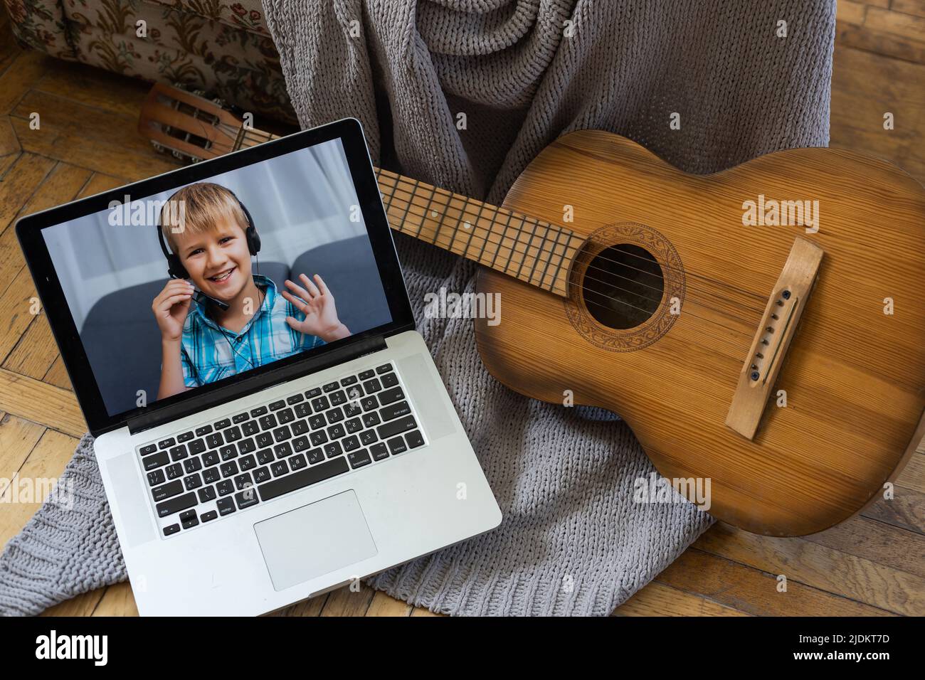 piccolo bambino che suona la chitarra acustica e guarda il corso online sul  portatile mentre si pratica a casa Foto stock - Alamy