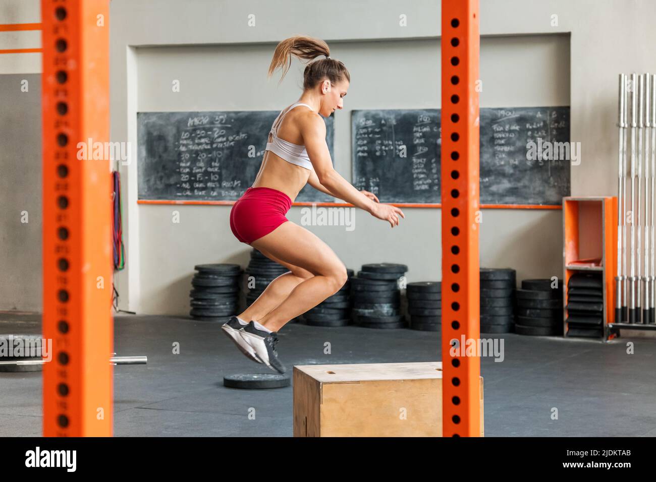 Giovane donna atletica che fa un Crossfit box salto esercizio in una palestra in un concetto di salute e fitness Foto Stock