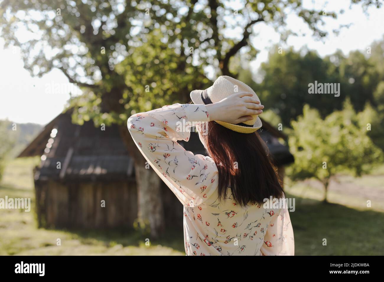 romantico ritratto di una giovane donna in paglia cappello e bel vestito in campagna in estate Foto Stock