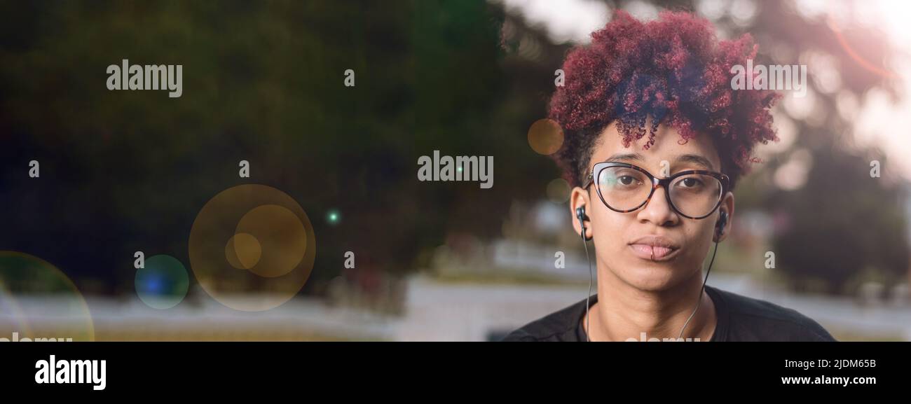 banner giovane donna colombiana latina, con occhiali e afro, indignata grave infastidito da abuso femminile, seduto guardando la macchina fotografica all'aperto al tramonto Foto Stock