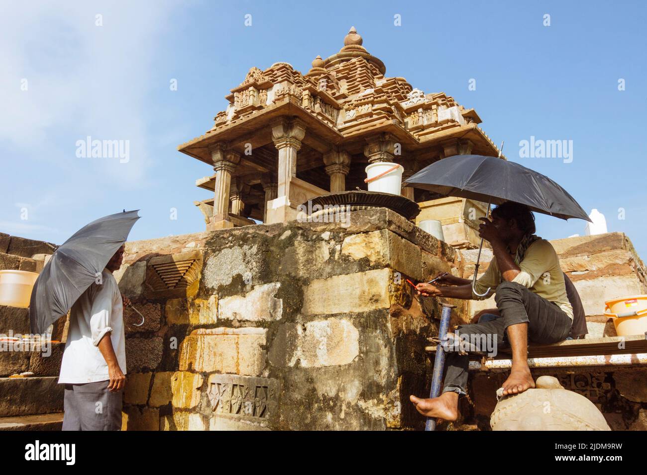 Khajuraho, Madhya Pradesh, India : due uomini che hanno gli ombrelli lavorano restaurando un santuario di Lakshmi parte del sito patrimonio mondiale dell'UNESCO Khajuraho Gruppo di Foto Stock