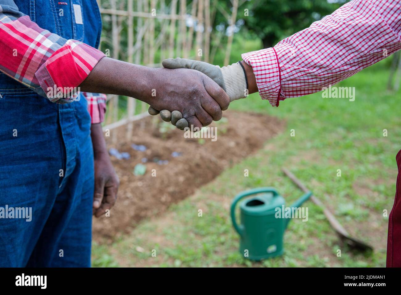 Due contadini africani scuotono le mani mentre lavorano nei campi Foto Stock