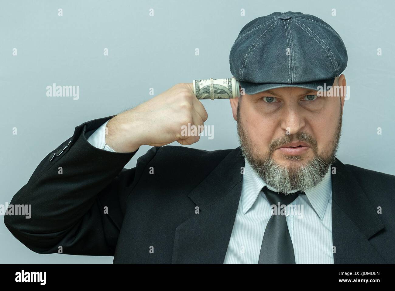 L'uomo mise il dito sul suo tempio. Il dito è avvolto in una fattura del dollaro. Sembra che voglia sparare a se stesso. Foto Stock
