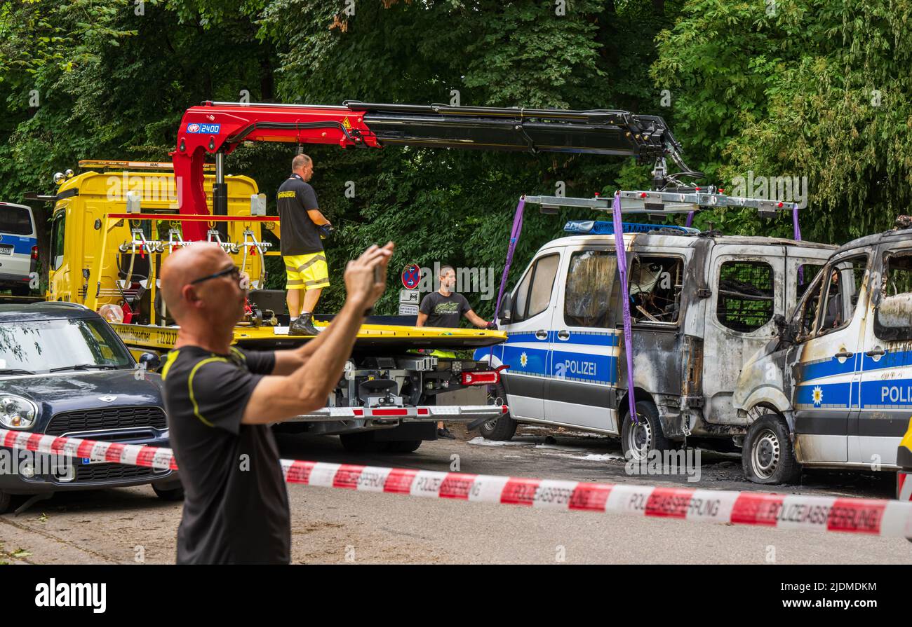 Monaco di Baviera, Germania. 22nd giugno 2022. Le auto della polizia bruciate che hanno preso il fuoco durante la notte sono prese da una società privata di traino. Gli autobus di squadra della polizia federale di sommossa sono parcheggiati davanti ad un hotel dove gli ufficiali di polizia sono alloggiati per la cima G7. Gli investigatori presumono che il fuoco sia stato causato da un'arsone. Credit: Peter Kneffel/dpa/Alamy Live News Foto Stock