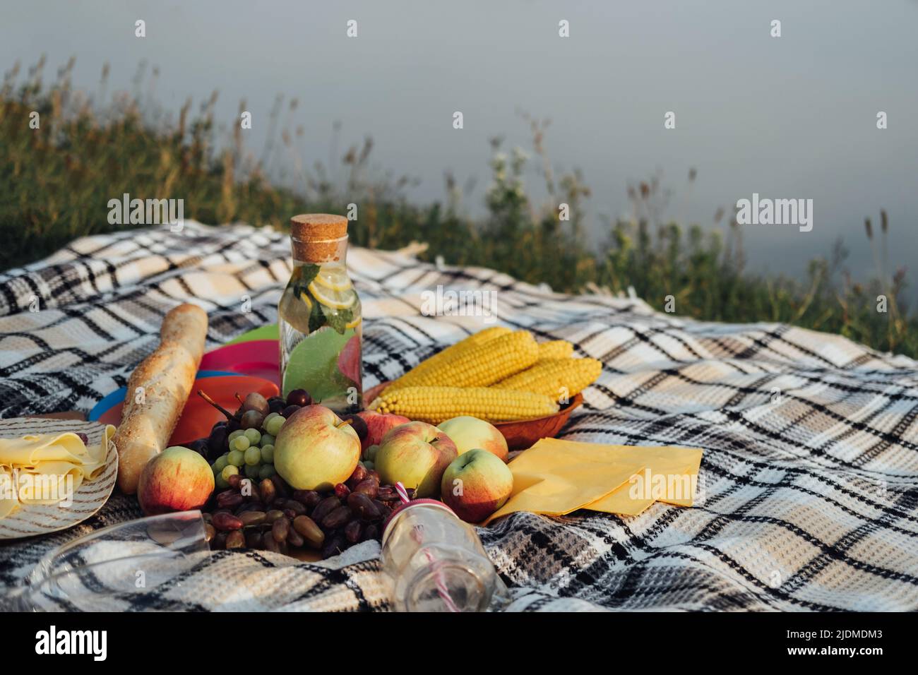Set da picnic, frutta e limonata posate sulla Plaid vicino al fiume al tramonto Foto Stock