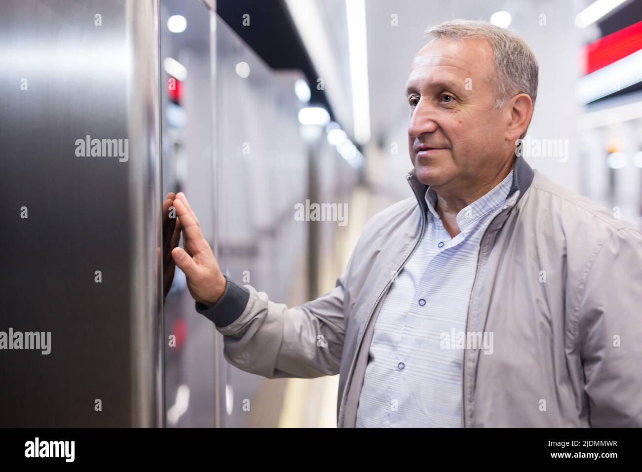 Uomo di mezza età in attesa di treno alla stazione della metropolitana Foto Stock