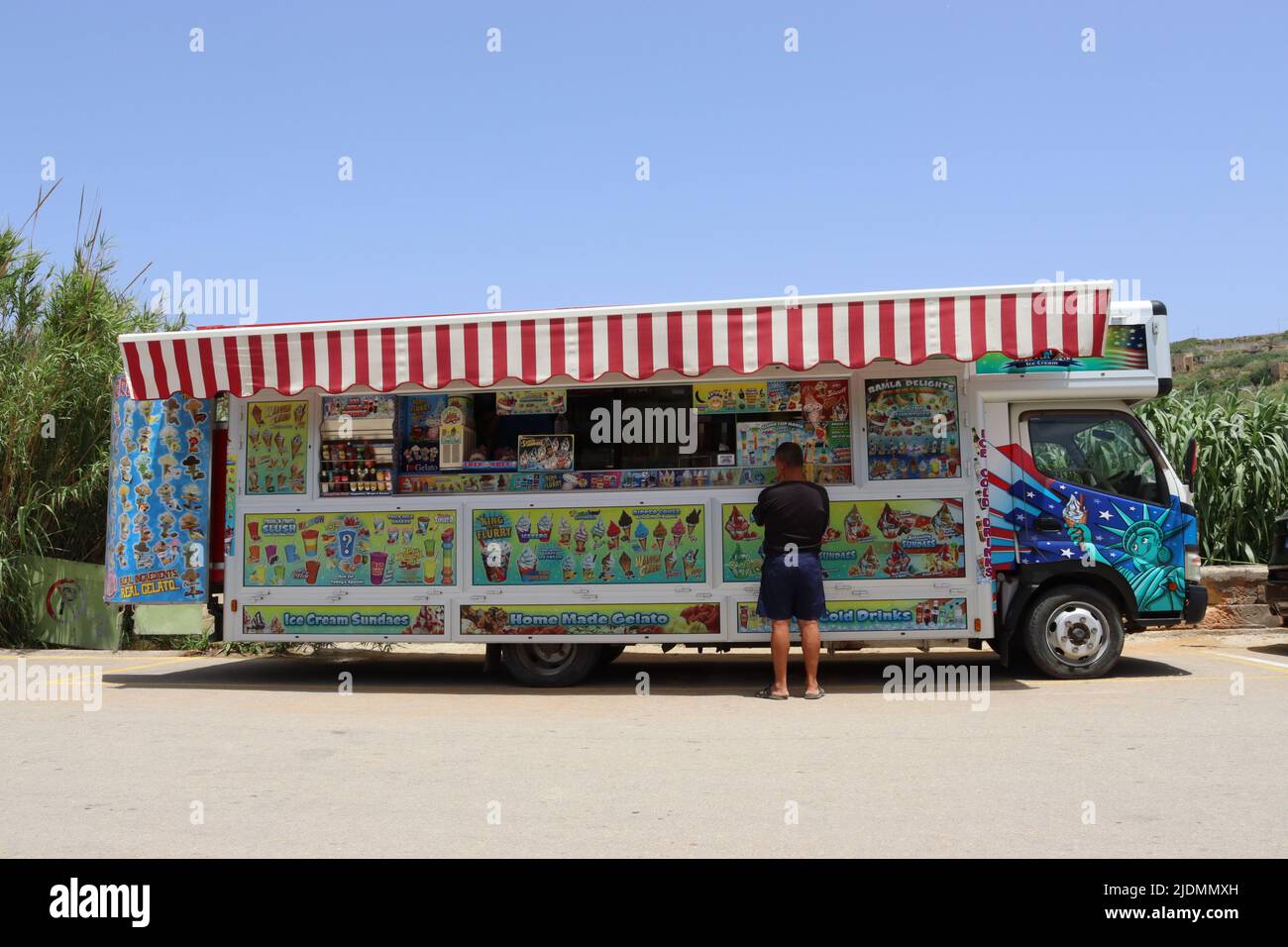 Un cliente bemused lotta per fare una scelta di che cosa comprare da un camion del gelato - scelte, scelte!! Foto Stock