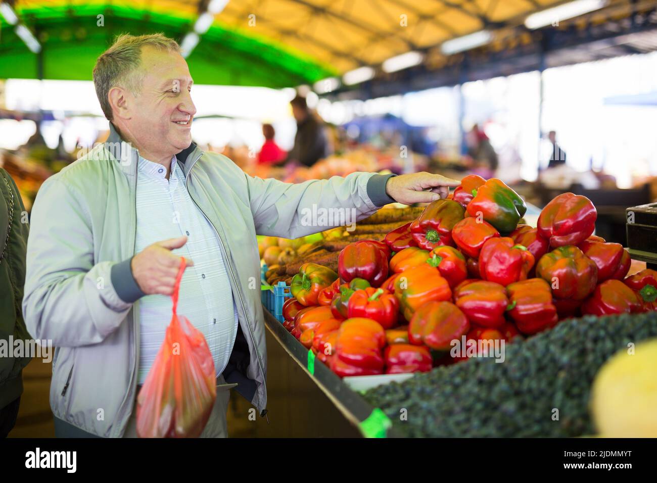 Uomo che acquista peperoni nel mercato Foto Stock