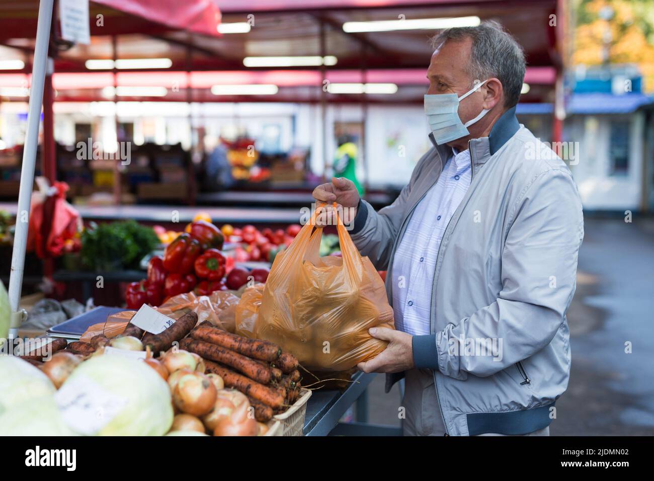 Uomo in maschera di faccia che acquista patate in gregrocery Foto Stock
