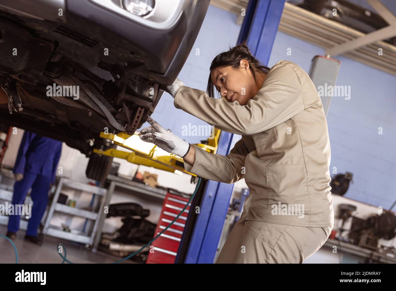 Vista laterale dell'ingegnere asiatico di metà adulto che esamina la vettura difettosa in officina, spazio di copia Foto Stock