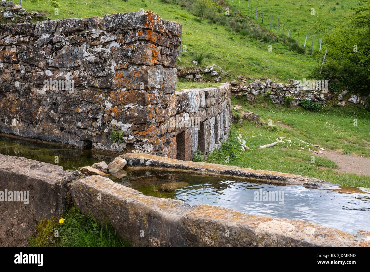 Spagna, Asturie. Parco Naturale di Somiedo. L'acqua fredda della sorgente della montagna raffredda il latte immagazzinato nei contenitori nel muro di pietra. Braña de Mumian. Foto Stock