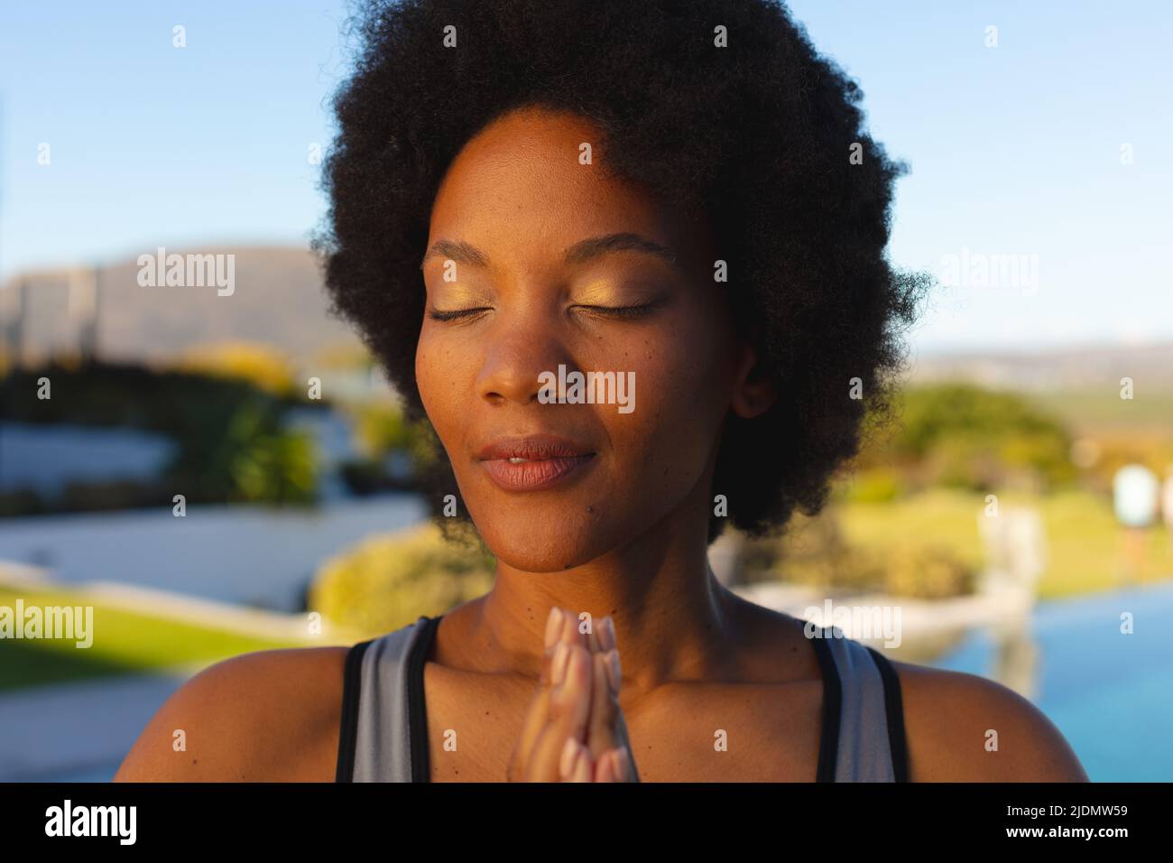 Primo piano della giovane afro afroamericana con gli occhi chiusi esercitandosi nel cortile Foto Stock