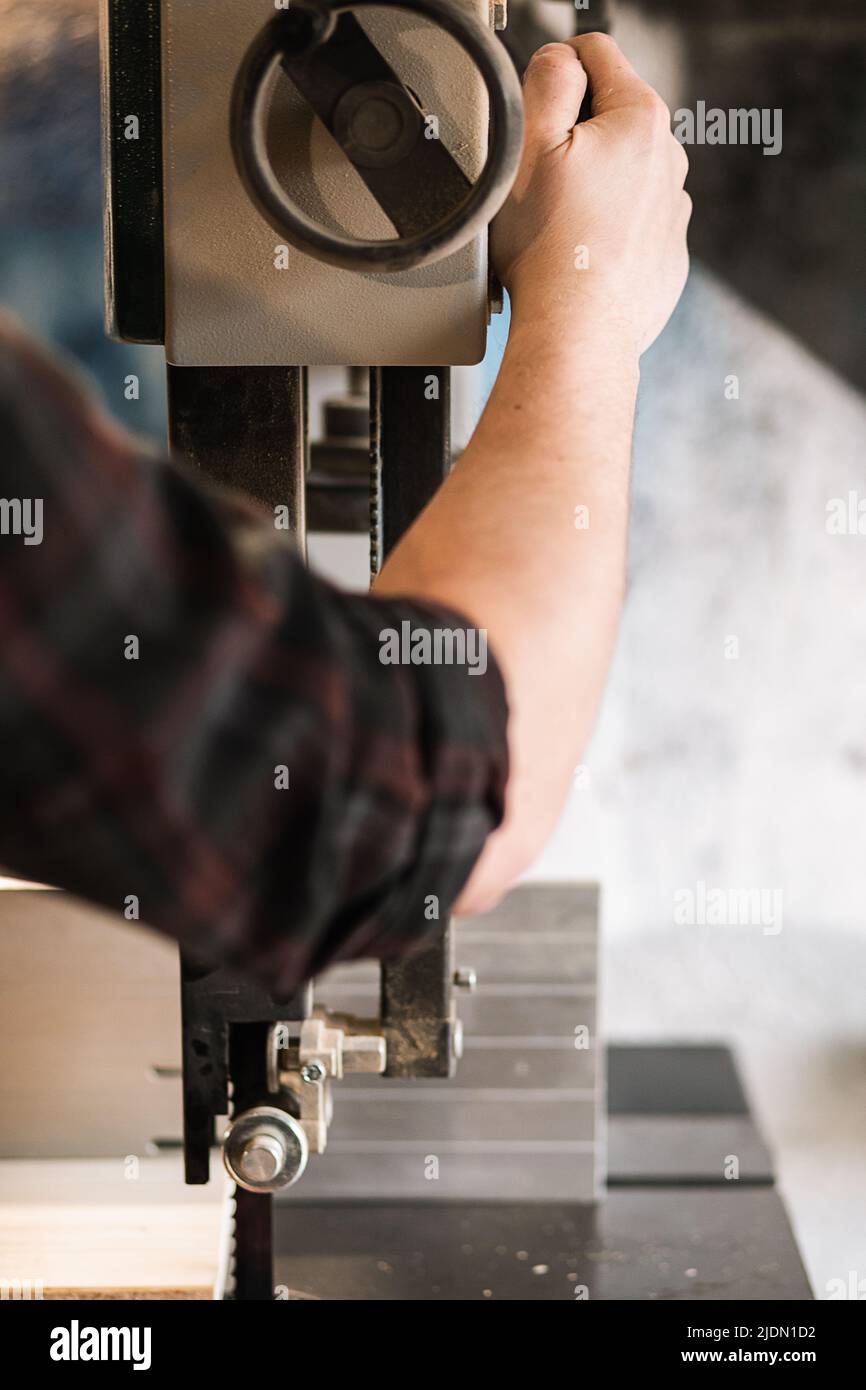 Le mani del lavoratore del falegname maschio del closeup non riconoscibili usano la macchina di spianatura della sega del macinacaffè, accendendo o la valvola sul pannello di controllo Foto Stock