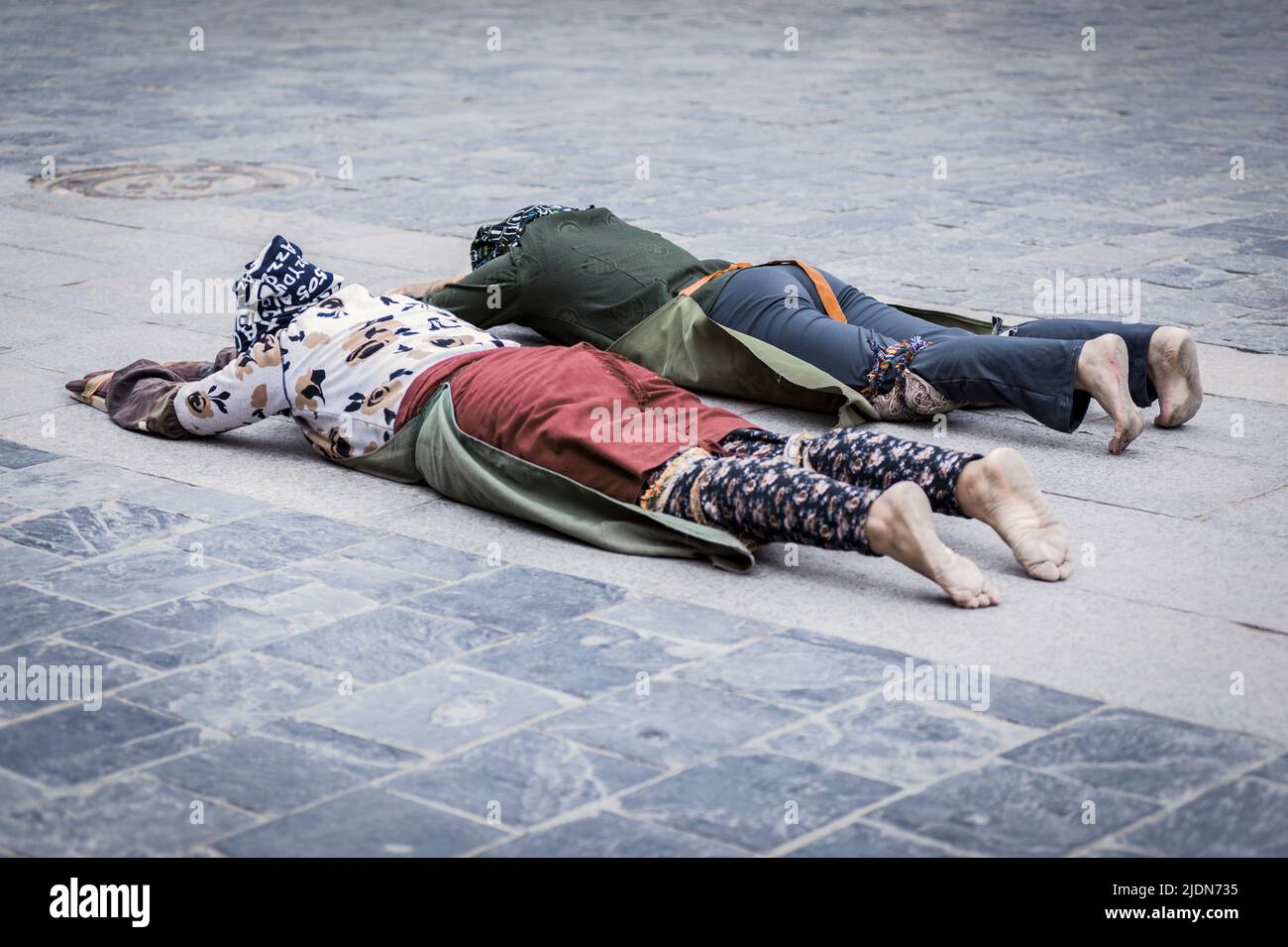 Pellegrini stesi sul pavimento dopo essersi prostrati. Facendo il 'Barkhor Kora', un circuito devozionale pellegrino intorno all'esterno della vecchia Jokhang T. Foto Stock