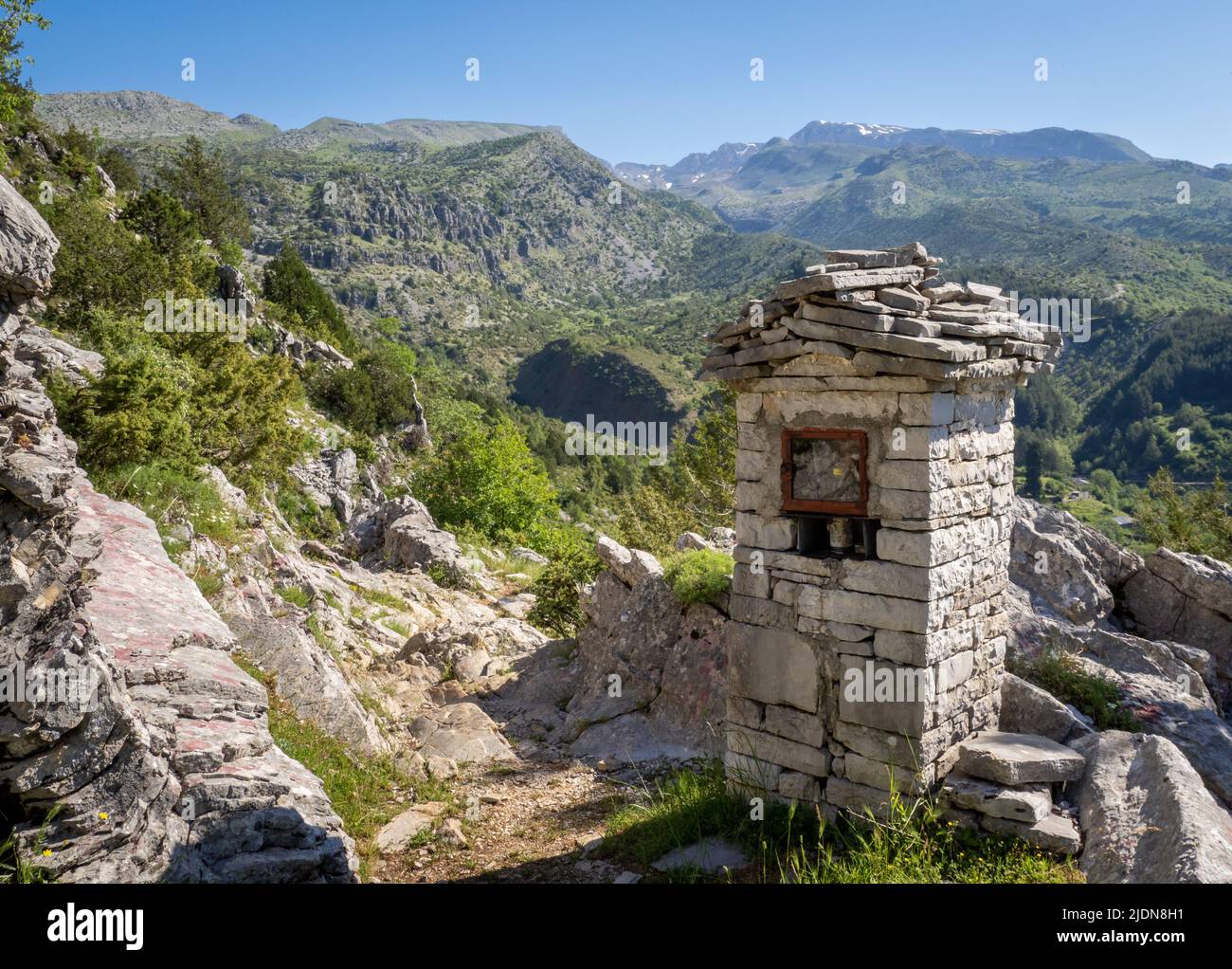 Sentiero ripido sopra il villaggio di Tsepelovo nella regione Zagori della Grecia settentrionale con il monte Timfi e la vetta Gamila in lontananza Foto Stock