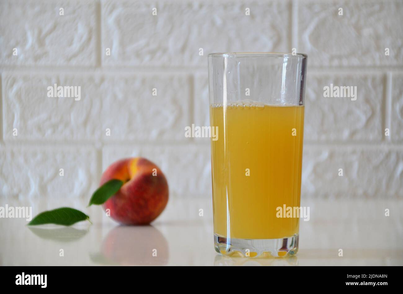 Succo di pesca fresco in bicchiere su sfondo bianco. Foto Stock